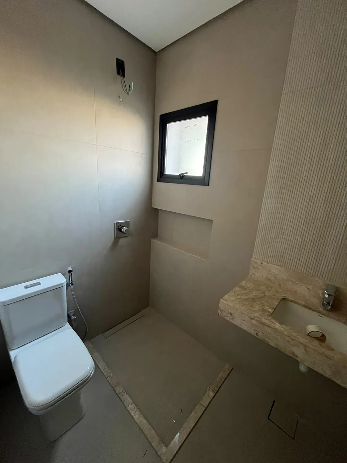 Banheiro com louça instalada, revestimento bege e cuba de mármore